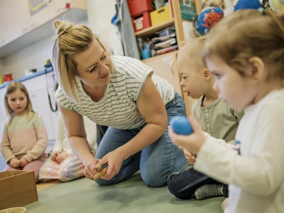 Eine Erzieherin sitzt mit Kindern im Morgenkreis einer CJD Kita.